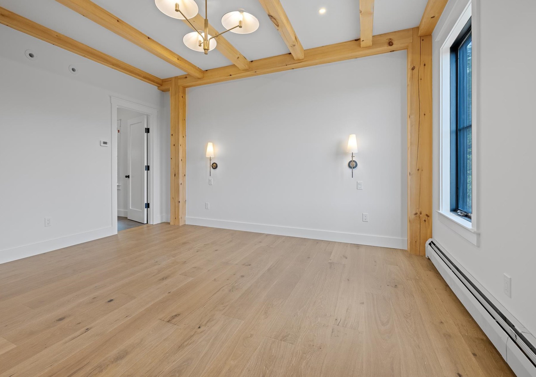 Main floor primary suite with exposed wood beams and light fixtures