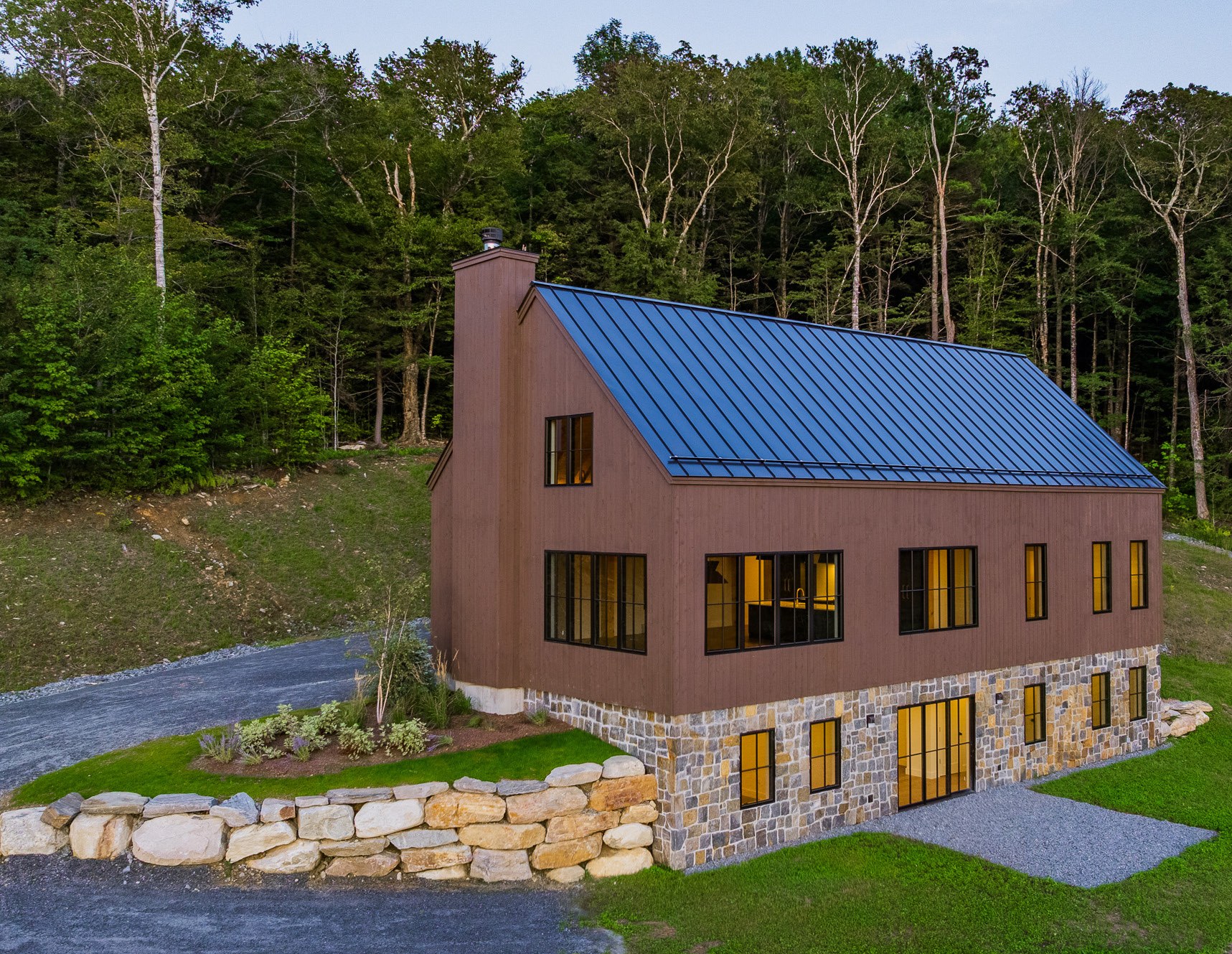 Stone Lodge exterior with stone foundation and wooded hillside